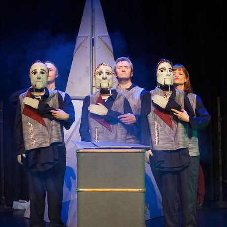 Three people, holding three puppets with their one arm folded across their shoulder.