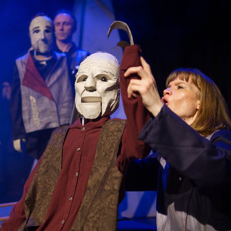 A person holding up the arm of a large puppet.