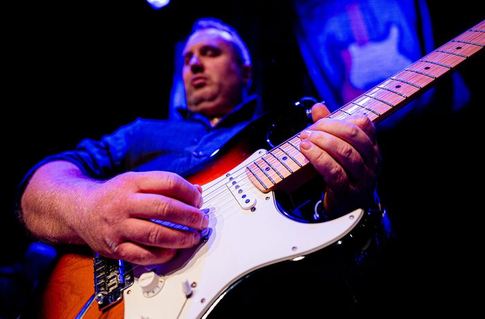 A person playing a Fender Stratocaster guitar.