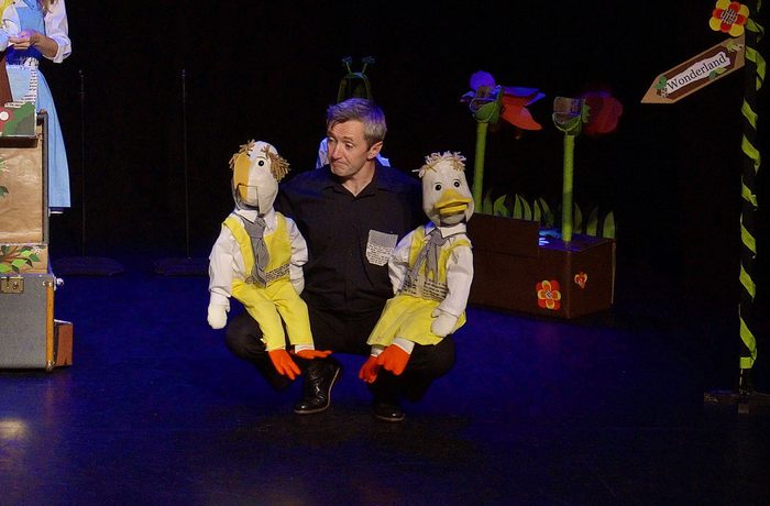 A performer with two duck puppets.