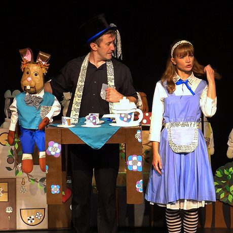 A performer dressed as Alice, with another performer carrying a tea set and operating a March Hare puppet.
