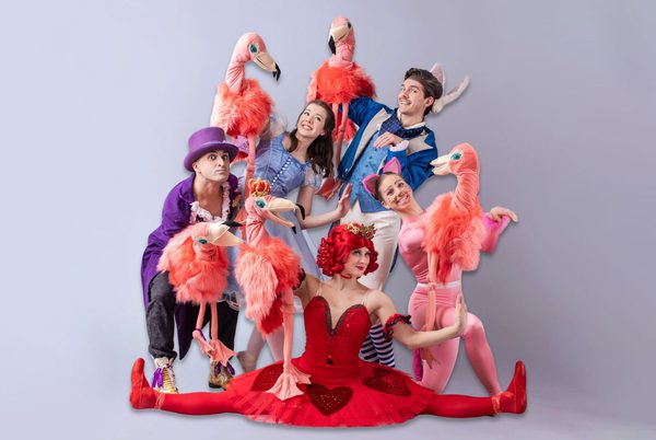 A group of people dresses as characters from Alice in Wonderland and holding pink flamingo puppets.