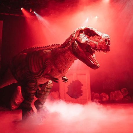 A large T-Rex puppet on a stage.