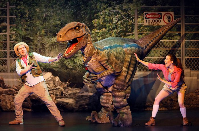Two people and a large velociraptor puppet.