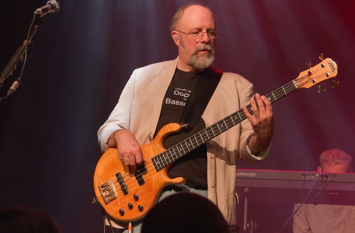 A person playing an electric base guitar