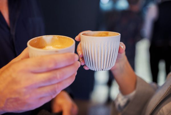 Two hands, each with a coffee mug