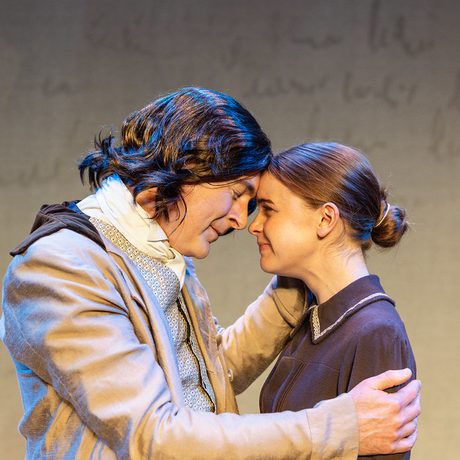 A man and woman in period costume, embracing.