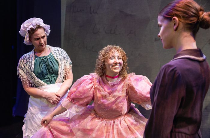 Three women in period costume dresses.