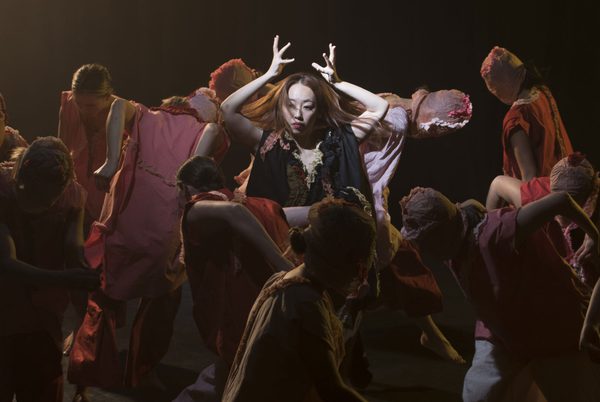 A large group of contemporary dancers performing on stage.