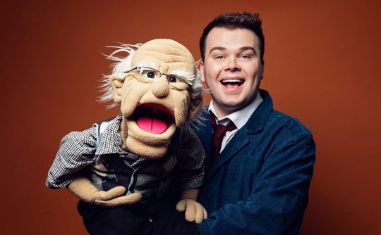 Max Fulham holding a puppet of an old man.