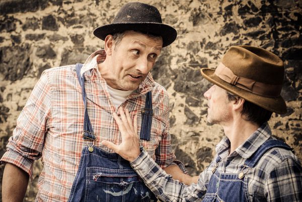 Two people dreesed as old farm hands wearing dungarees and hats