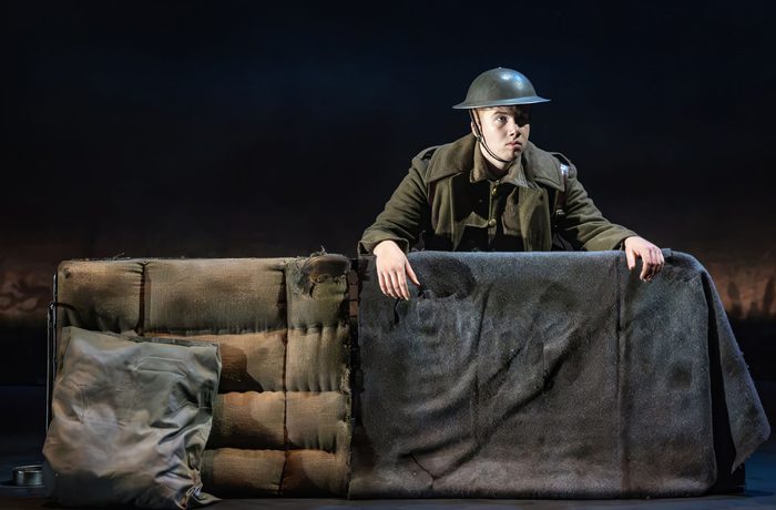A performer dressed as a World War 2 soldier behind a "trench".