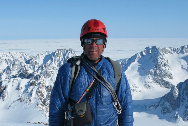 Simon Yates wearing mountaineering clothes, standing on snowy mountain peaks.