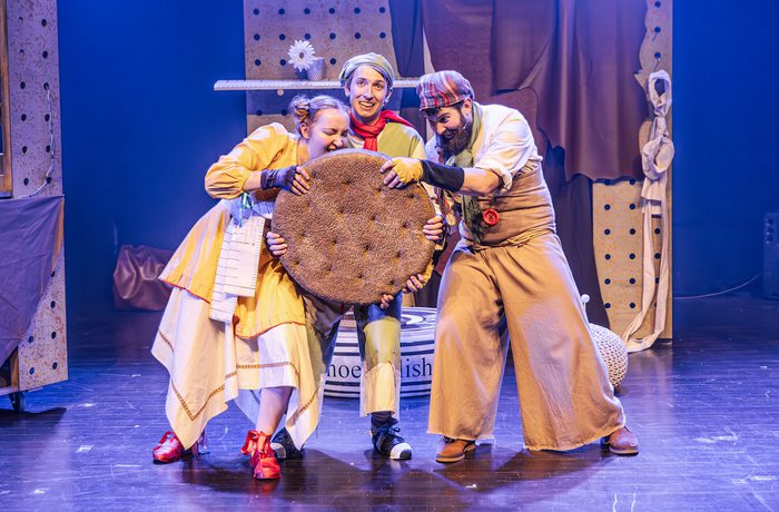 Three performers eating a giant biscuit