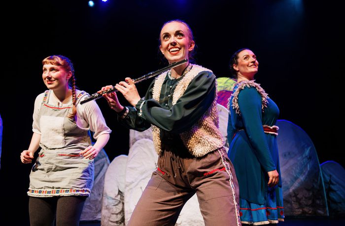 Three performers on stage. One is playing the flute.