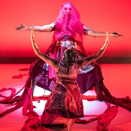 Dancers posing, lit up in a bright red light.
