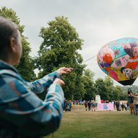 A person holding a rope to a hot air ballon.