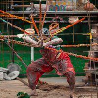 A person tangled in ropes and covered in clay.