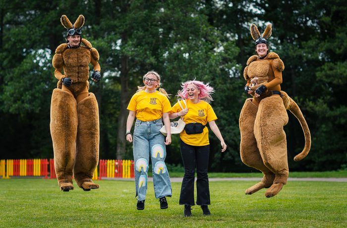 Four people jumping in to the air. Two of them are dressed as kangaroos.