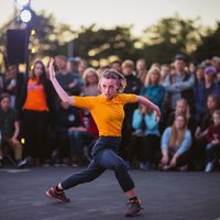 A contemporary dancer in front of a large crowd outside.