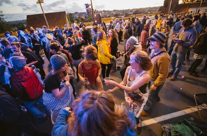 A group of people dancing on a carpark rooftop.