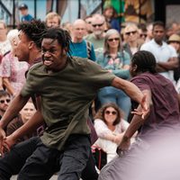 Contemporary dancers performing outside to a large crowd.