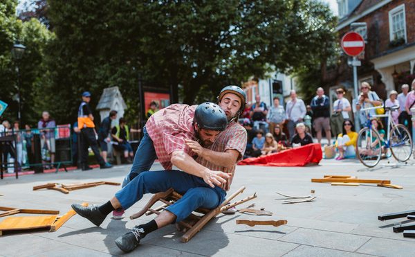 Two street performers sitting on a broken chair.