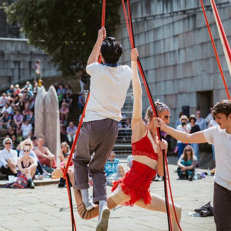 Acrobats performing with ropes to an outdoor crowd.