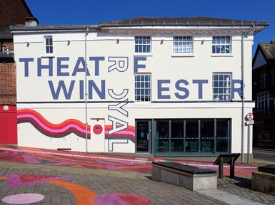 A daytime photo of Theatre Royal Winchester, with colourful artwork across the building and in the streets