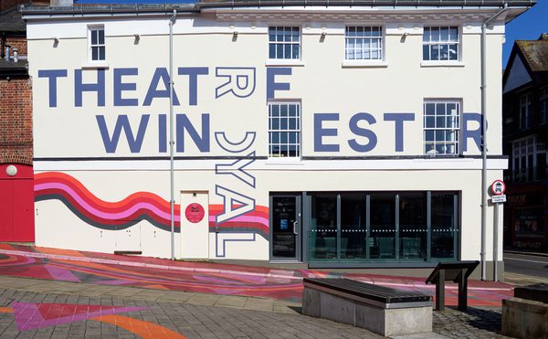 A daytime photo of Theatre Royal Winchester, with colourful artwork across the building and in the streets