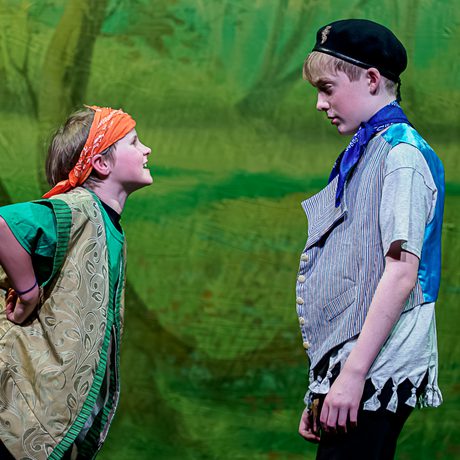 Young performers on stage against a green forest backdrop
