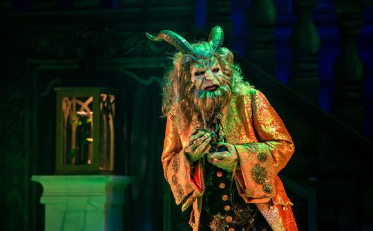 A performer dressed as the beast from Beauty and the Beast in low lighting.