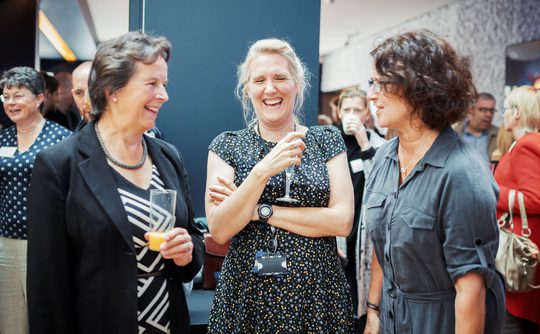 Three people chatting and laughing in the foyer of Theatre Royal Winchester.