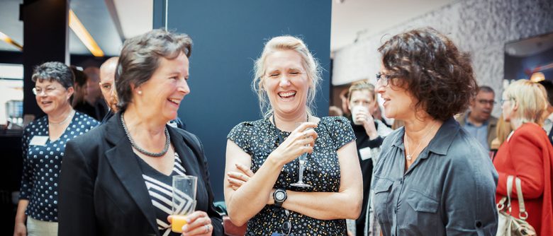 Three people chatting and laughing in the foyer of Theatre Royal Winchester.