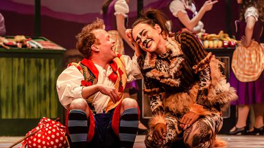 Two panto performers, one in a cat costume getting a fuss of the other performer.