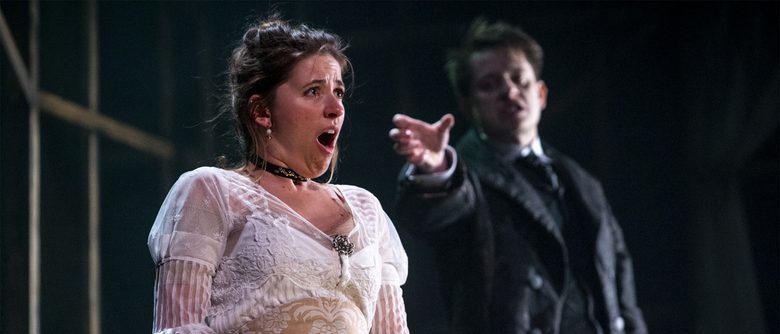 A person in a white dress sat looking horrified as a performer reaches for them from behind.
