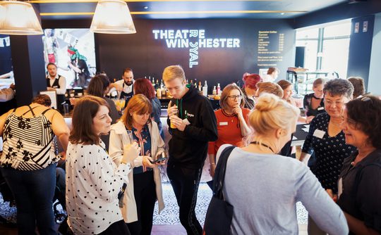 A crowd of people in conversation in the bar area of Theatre Royal Winchester.
