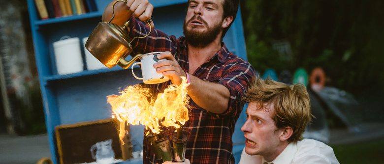 A person holding up a large flame, whilst another person is poring a cup of tea above the flame.