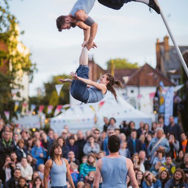 Aerial acrobats performing outside in front of a large crowd
