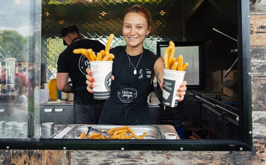 A person holding two cups full of churros.
