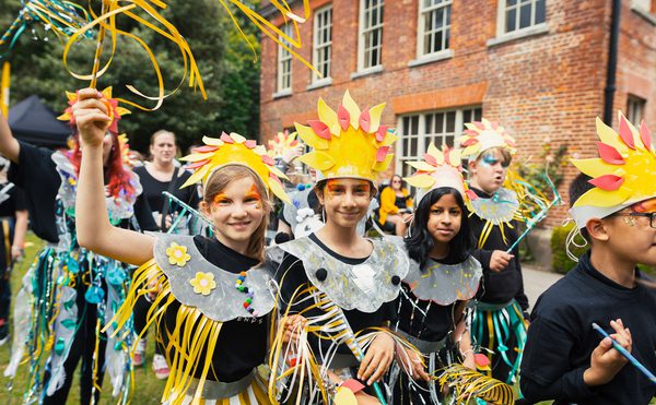 Young people dressed in yellow and silver carnival costumes looking happy.
