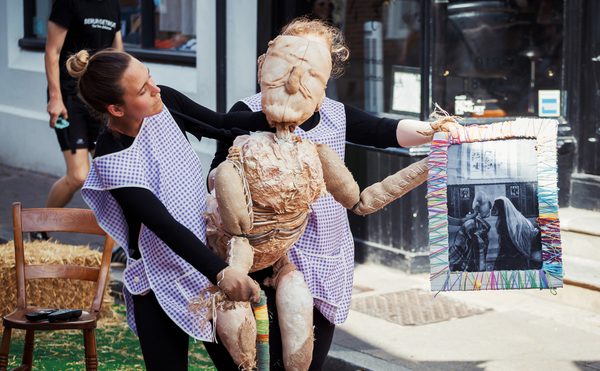 Two puppeteers operating a puppet outside.