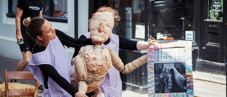 Two puppeteers operating a puppet outside.
