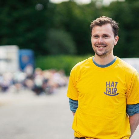 Volunteer wearing a yellowing Hat Fair t-shirt and smiling.
