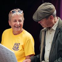 A smiling volunteer holding up a timetable for a member of the public.