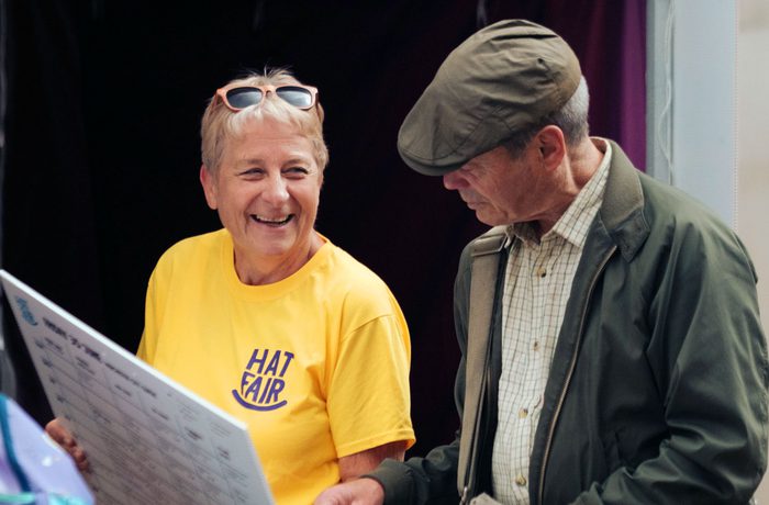 A smiling volunteer holding up a timetable for a member of the public.