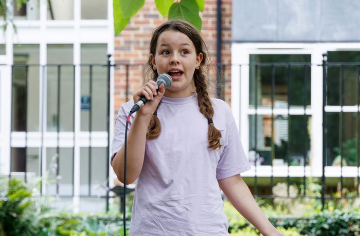 A young performer with a mic outdoors.