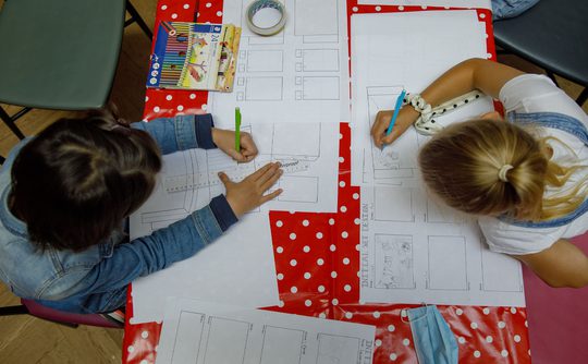 Two young people at a table drawing and crafting.