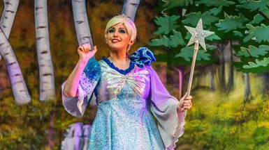 A panto performer dressed as fairy carry a wand.
