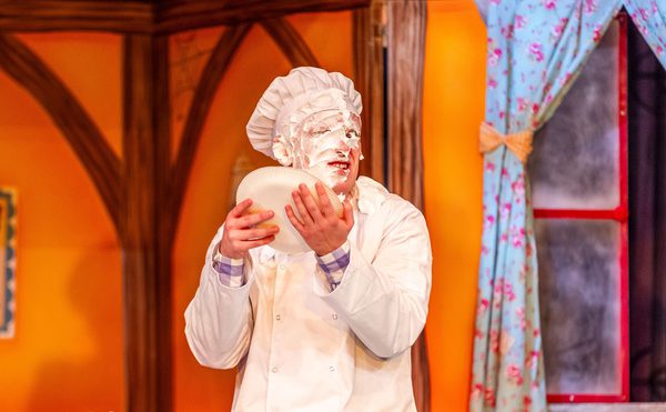 A panto performer dressed as a chef with a face full of cream.
